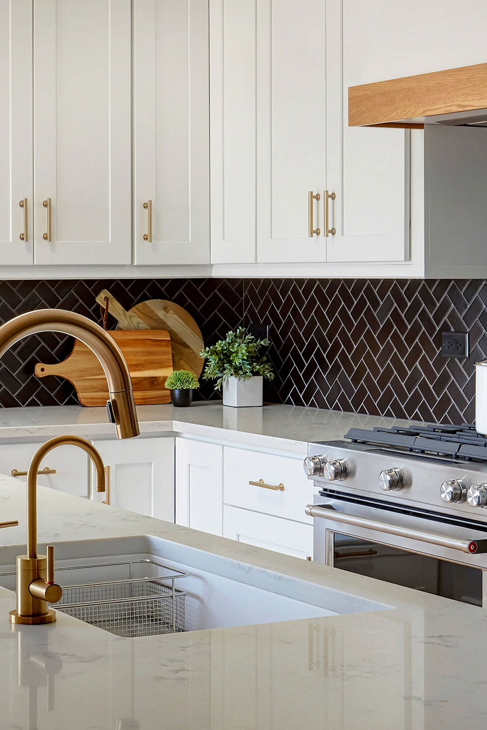 White shaker kitchen with dark herringbone backsplash and brass fixtures